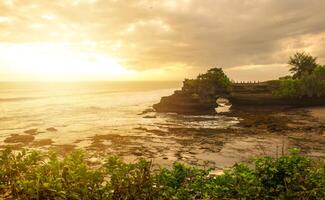 hermosa puesta de sol ver de pura batu bolong un icónico hinduismo mar templo por poco tanah lote templo en bali isla de Indonesia. foto