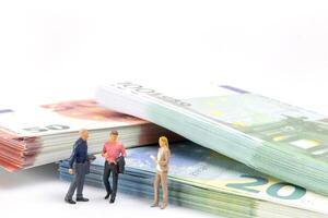 miniatura empresario navega el financiero paisaje, rodeado por euro billetes de banco, foto