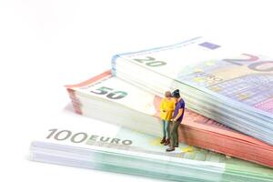 Miniature businessman navigates the financial landscape, surrounded by Euro banknotes, photo