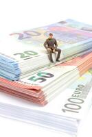 Miniature businessman navigates the financial landscape, surrounded by Euro banknotes, photo