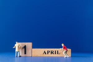 Miniature people painting a wooden block on April 1st photo