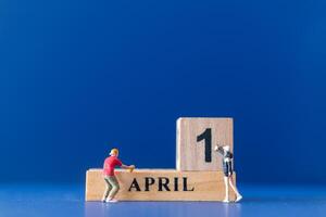 Miniature people painting a wooden block on April 1st photo