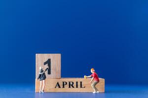 Miniature people painting a wooden block on April 1st photo