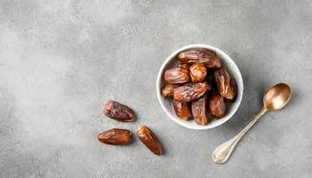 AI generated A top view of A bowl of juicy dates with bronze spoon on a textured grey surface, capturing the essence of Ramadan. Ideal for iftar invitations or Ramadan greetings. Top view, Flat lay. photo