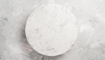 AI generated A top view of a round, white concrete pedestal on a white textured concrete table, ideal for food display or recipe presentations, flatlay background photo