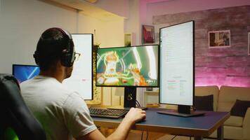 Excited young man about his victory wearing headphones while streaming an online shooter. Two streaming charts opened on separate displays video