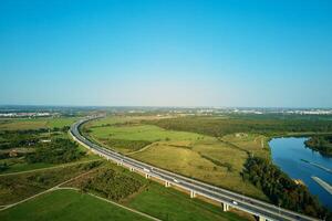 Cars driving on highway road near green fields, top view photo