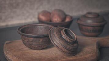 Clay pot with open lid and plate with potatoes photo