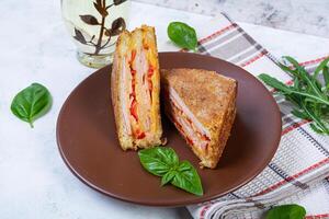 Sandwiches fried in breadcrumbs with ham, cheese and tomatoes photo