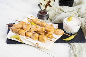 Chicken kebab with sour cream sauce. Chicken skewers on wooden background photo