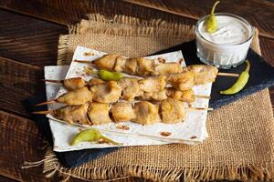 Chicken kebab with sour cream sauce. Chicken skewers on wooden background photo