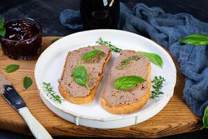 Grilled sandwich with pate with chicken liver and olives on dark background photo