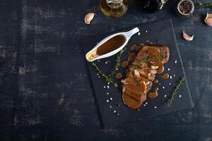 Grilled beef steak with herbs and spices on stone plate photo
