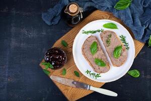 Grilled sandwich with pate with chicken liver and olives on dark background photo