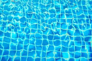 blue water wave pattern in swimming pool as the sun shines down during the day. Soft and selective focus. photo