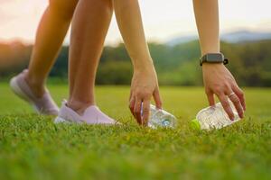 People help pick up trash from plastic bottles left on the lawn. Soft and selective focus. photo