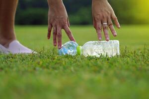 personas ayuda recoger arriba basura desde el plastico botellas izquierda en el césped. suave y selectivo enfocar. foto