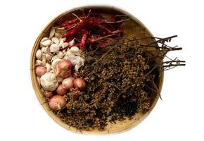 isolated dried chilies, Zanthoxylum, garlic cloves and shallots on a bamboo basket on a white background. It is an ingredient in Thai curry paste. photo