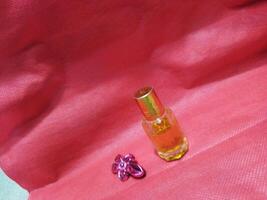 un pequeño botella de perfume sentado en un rojo paño foto