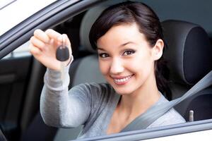 Happy owner of a new car is showing the car key. Pretty girl driver photo