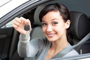 Happy owner of a new car is showing the car key. Pretty girl driver photo