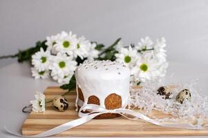 Easter cake in glaze stands on a board with quail eggs and white flowers photo