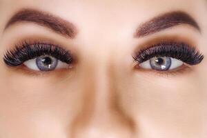 Eyelash Extension Procedure. Woman Eye with Long Eyelashes. Close up, selective focus. Hollywood, russian volume photo