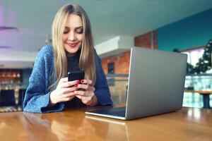 Woman typing text message on smart phone in a cafe. Young woman sitting at a table with a coffee using mobile phone. With blank copy space scree for your advertising text message or promotional photo