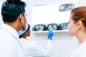 Multiracial dental team checking teeth x ray of patient. Dental clinic concept. photo