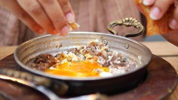 women eating Turkish scrambled eggs with roasted meat in copper pan video