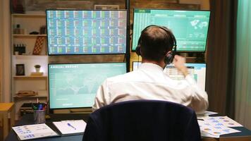 tillbaka se av stock marknadsföra mäklare ser på grafer på flera olika monitorer från Hem kontor. video