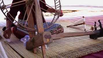 Close-up of a woman spinning thread in a spinning machine which is a tool used to spin cotton into tight threads threads. Thailand traditional. video