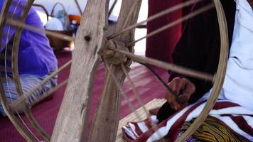 Close-up of a woman spinning thread in a spinning machine which is a tool used to spin cotton into tight threads threads. Thailand traditional. video