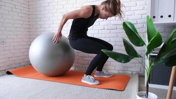 fitness, sport en een gezonde levensstijl. jonge vrouw die thuis traint met stabiliteitsbal of fitnessbal. thuistraining video