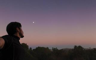 Thoughtful man looking at the sky with beautiful sunset in the background and space for text photo