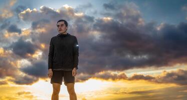 Serious man wearing sportswear, sky in the background representing effort, with space for text photo