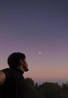 pensativo hombre mirando a el cielo con hermosa puesta de sol en el antecedentes y espacio para texto foto