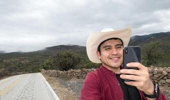 hombre en sombrero haciendo vídeo llamada con su teléfono en zona con pobre señal, con espacio para texto foto