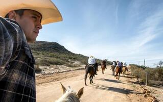 Man taking a walk with friends on horseback in hat through semi-deserted countryside, with space for text photo