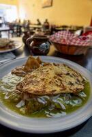 Homemade food Mexican chilaquiles with green sauce, chicken, tortilla chips and beans photo