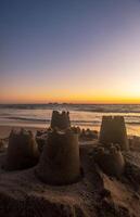 arena castillo hecho por niños en el playa con hermosa puesta de sol en el playa, con espacio para texto foto