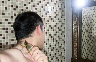 Man cutting his own hair with a clipper, with space for text photo