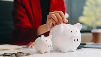 Close up young female putting coin in piggy bank. Woman saving money for household payments, utility bills, calculating monthly family budgets, making investments or strategy for personal savings. video