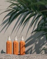 3 mockup cosmetic spray bottles on the gravel floor, blur the trees in the foreground. 3D rendering photo