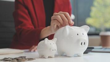 Close up young female putting coin in piggy bank. Woman saving money for household payments, utility bills, calculating monthly family budgets, making investments or strategy for personal savings. video