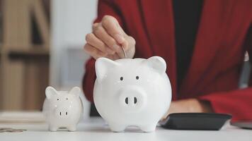 Close up young female putting coin in piggy bank. Woman saving money for household payments, utility bills, calculating monthly family budgets, making investments or strategy for personal savings. video