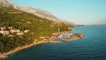 costa di makarska Riviera nel Croazia. porto a il piede di biokovo montagne. caldo splendore di il sera sole con azzurro acque di il Adriatico mare. video