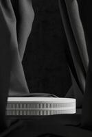 White cylindrical pallet on a black velvet curtain backdrop. Abstract background for product presentation. 3D rendering photo