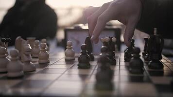 spielen Schach im das Park beim Sonnenuntergang. Stücke auf ein Schachbrett. video