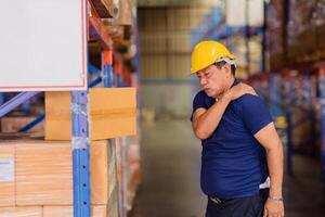 warehouse worker back shoulder muscle pain injuries from heavy lifting hard working. photo